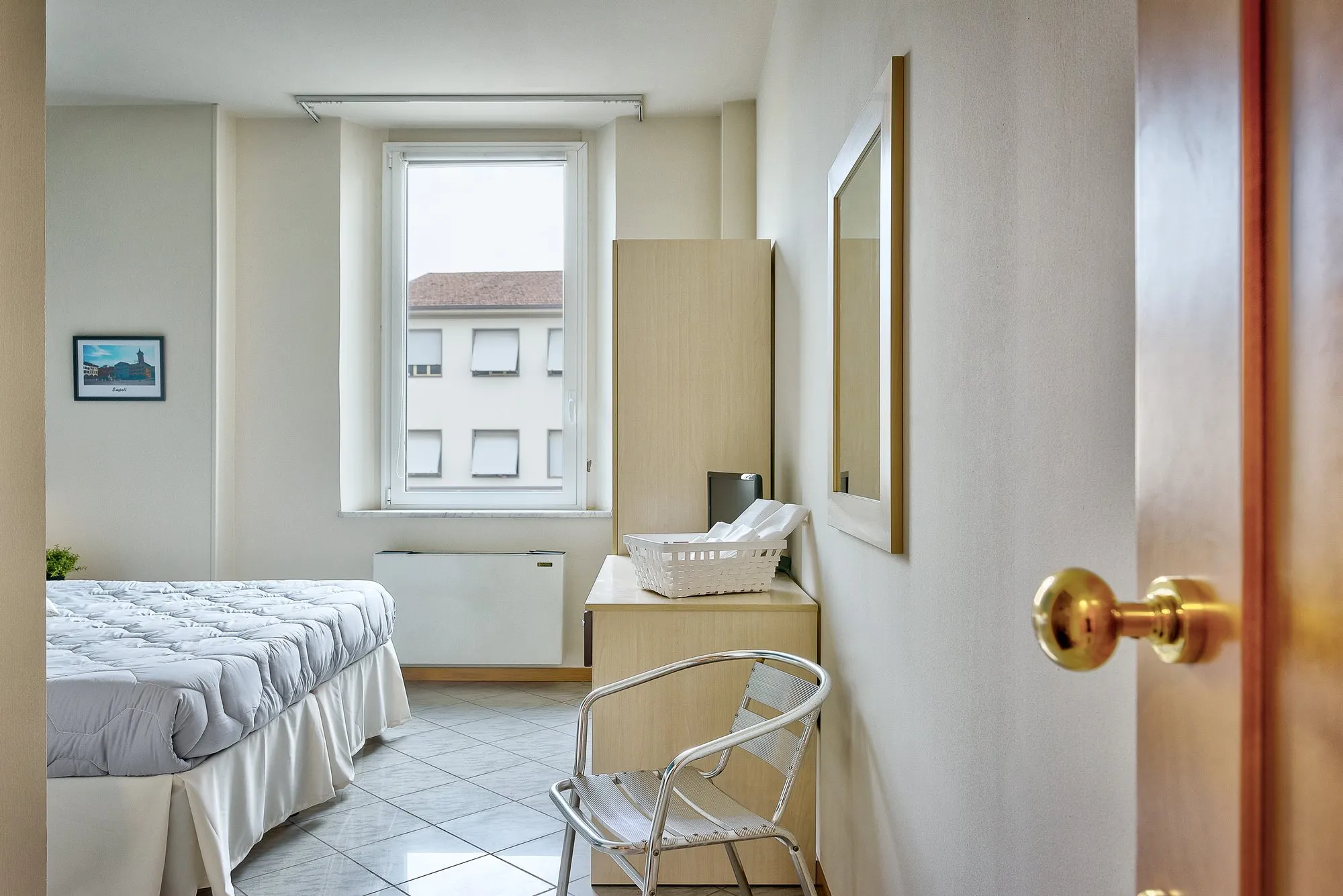 Letto, armadio e sedia accanto alla finestra