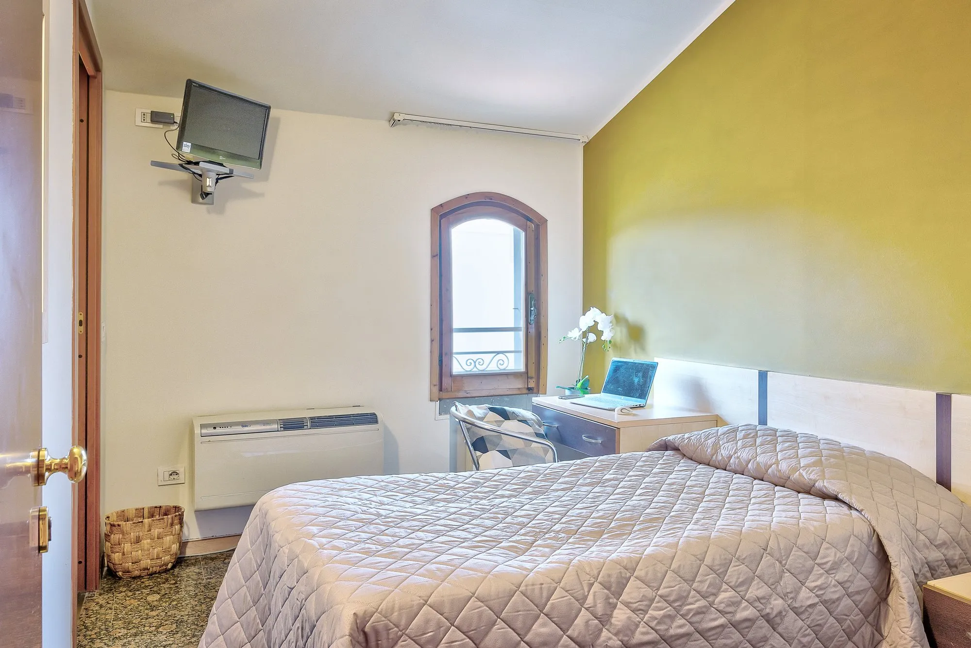 Letto e scrivania sotto la finestra ad arco