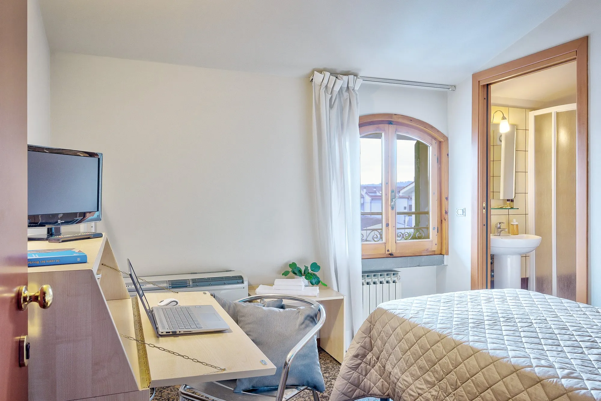 Scrivania, TV e letto accanto alla finestra ad arco
